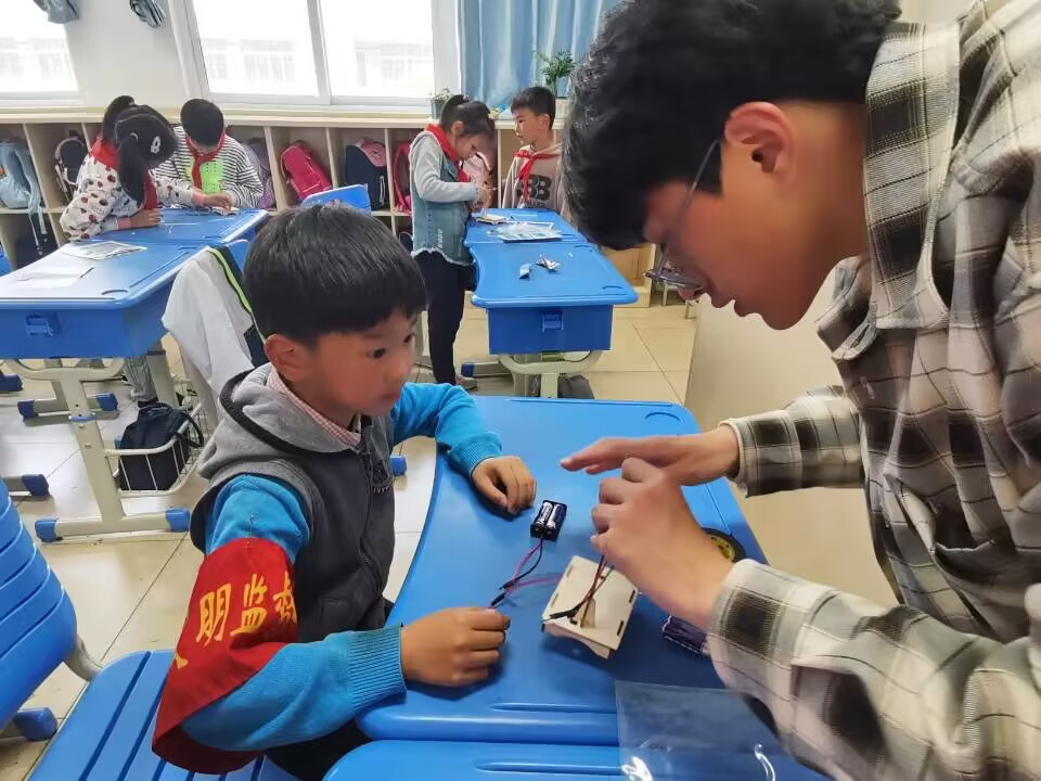 图为必赢bwin官网登录入口自动化学院志愿者蔡志锦帮助润商小学二年级一班同学连接电路.jpg